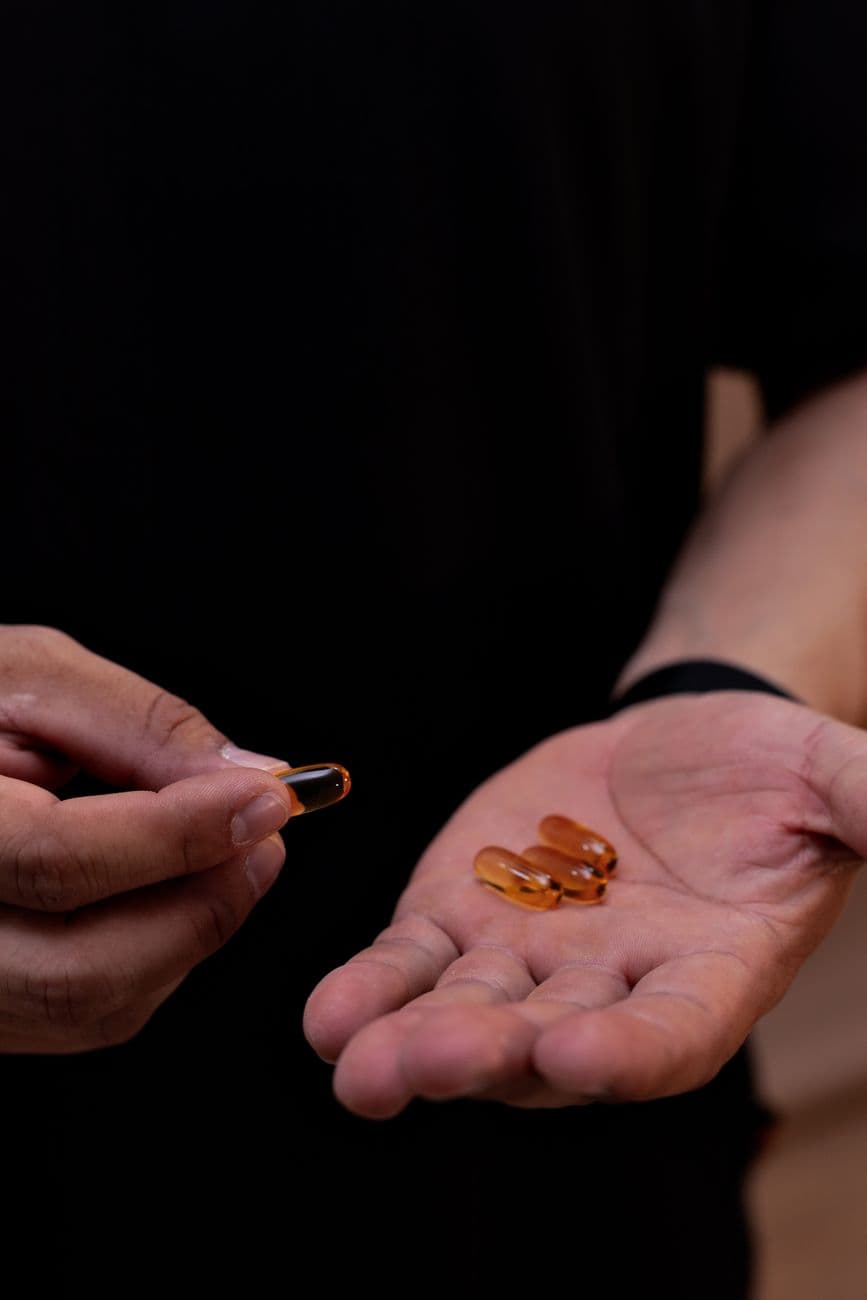 GOMAXXX amber performance capsules held in hand against a dark backdrop