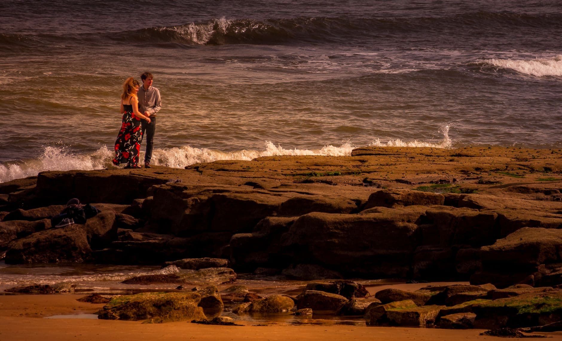 A couple embracing on the shoreline at golden hour
